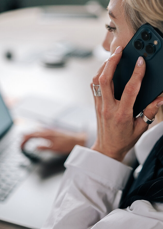 Frau sitzt telefonierend am Schreibtisch